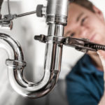 plumber tightening pipe AC Company in Aitkin
